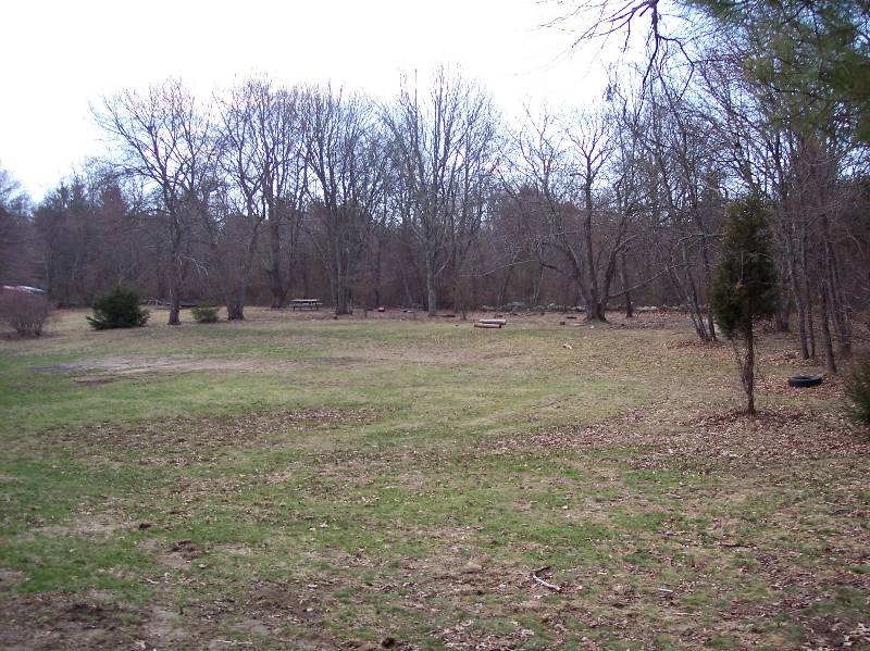 Outdoor camping area at Camp Aquapaug with trees and open grassy fields.
