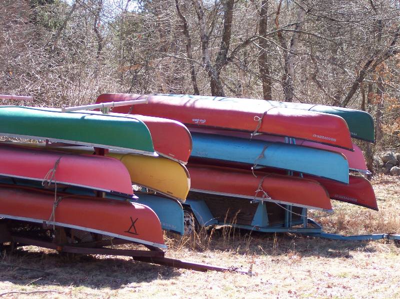 Canoes and kayaks stacked outdoors at Camp Aquapaug, Narragansett Council.