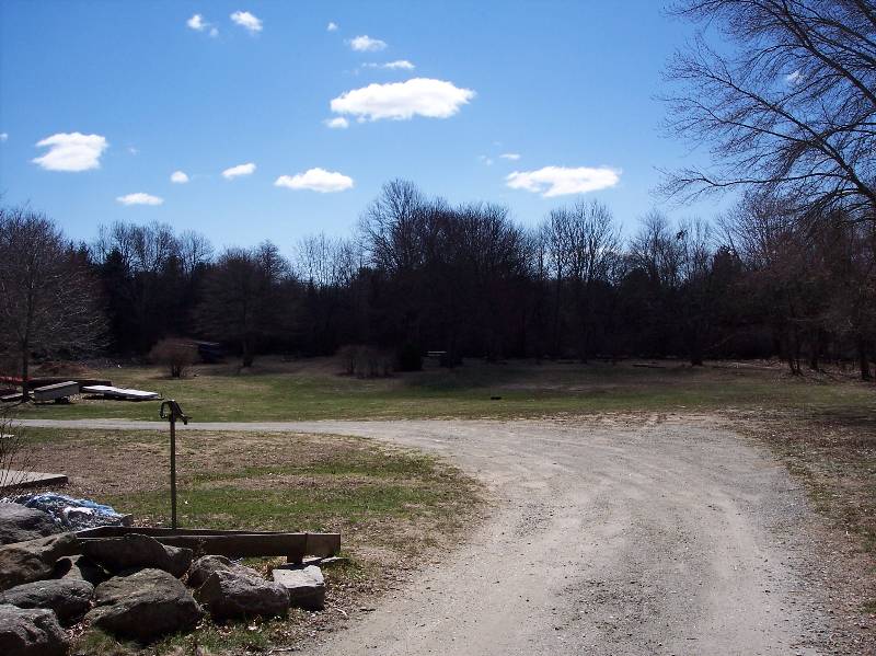 Scenic view of Camp Aquapaug with open field, trees, and blue sky.