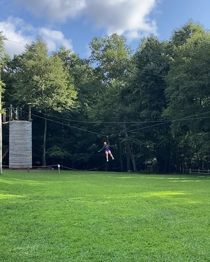 Youth enjoying zip line activity during team building outdoor trip.