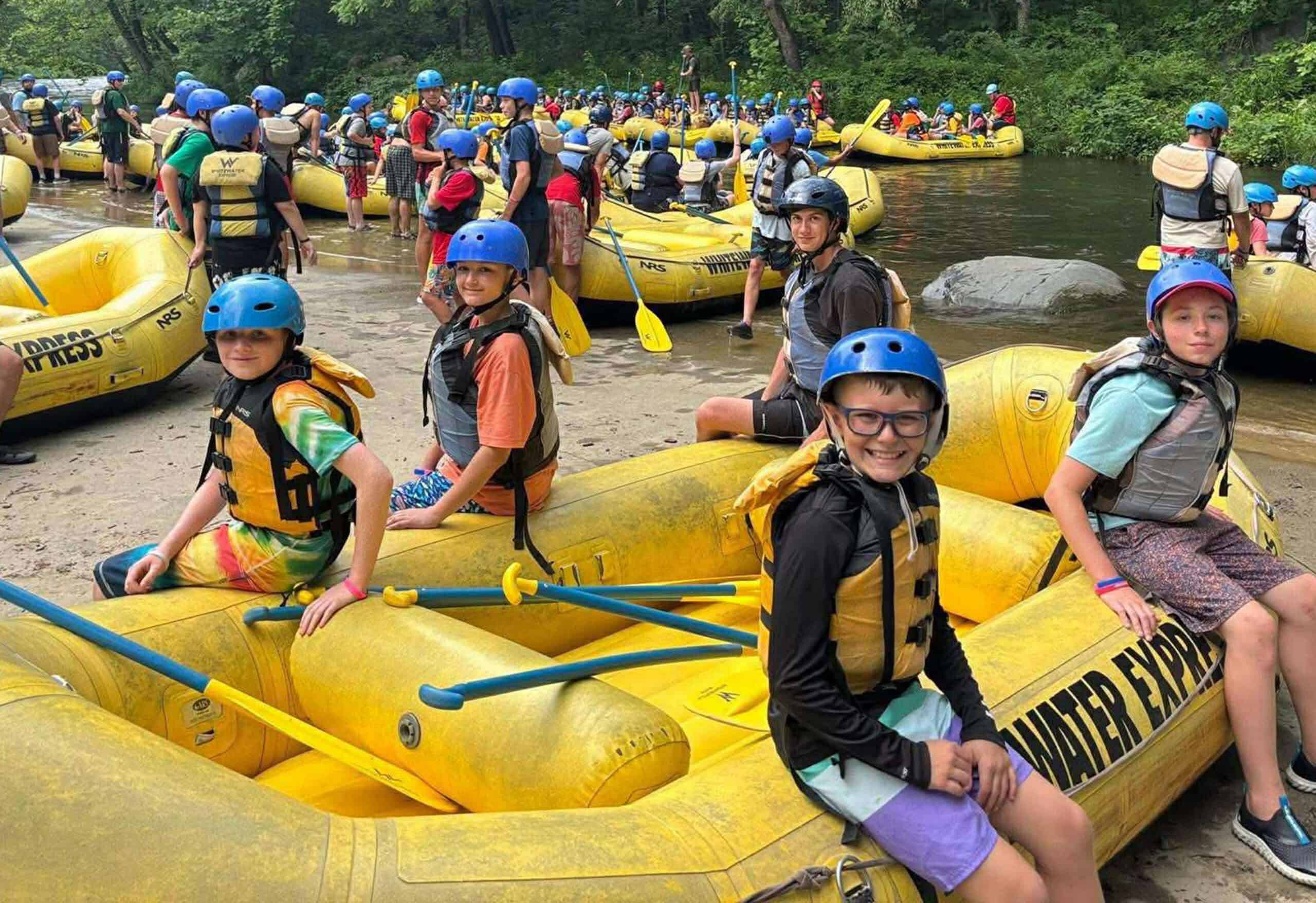 Rafting at Camp Yawgoog with youth participants wearing helmets and life jackets.
